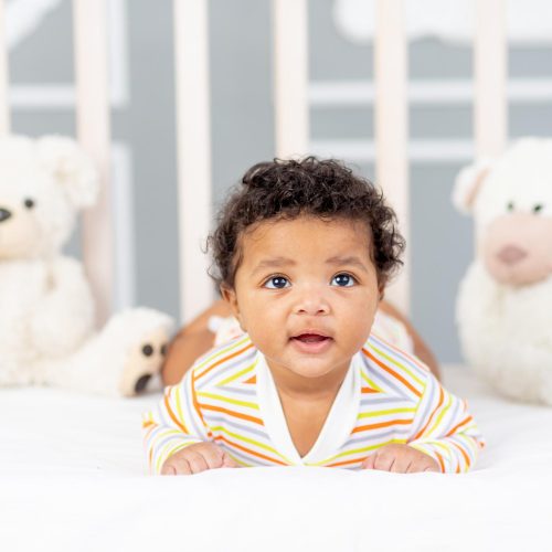 africanamerican-small-child-lying-bed-orange-clothes-with-soft-bears